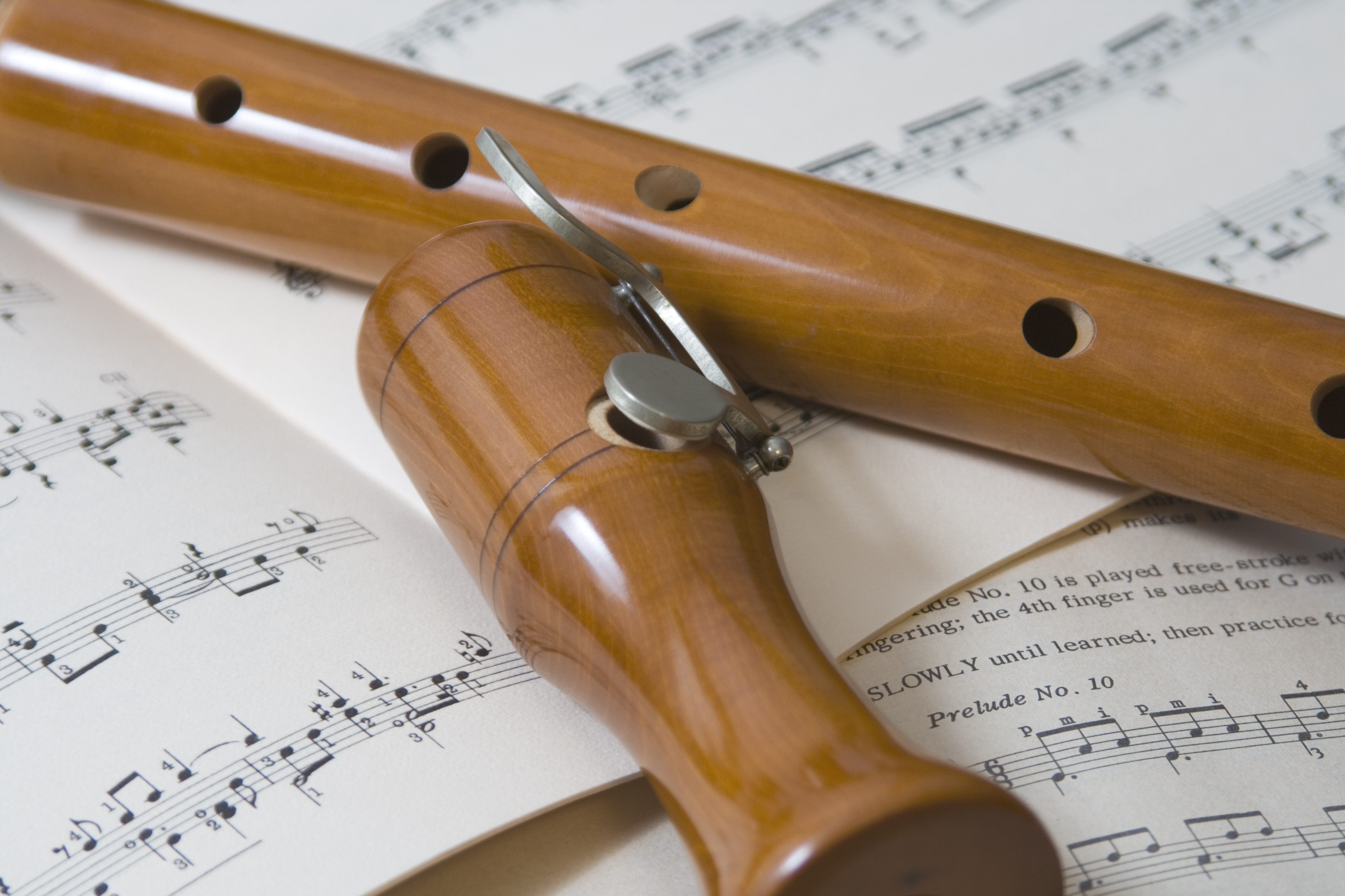 An artistic image of a wooden recorder resting on some sheet music, symbolising the recorder ensembles