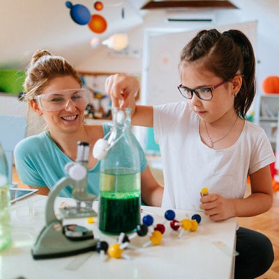 Little girl doing science lesson with test tubes and teacher. Representing Preparing for Statutory Assessment at the End of KS1 for Science