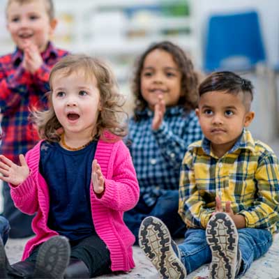 Children sat on the carpet in a classroom listening to the teacher. Representing fundamental British values and SMSC