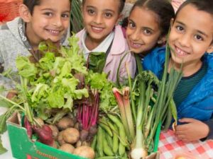 Children next to some lovely vegetables. Representing Health For Life Programme