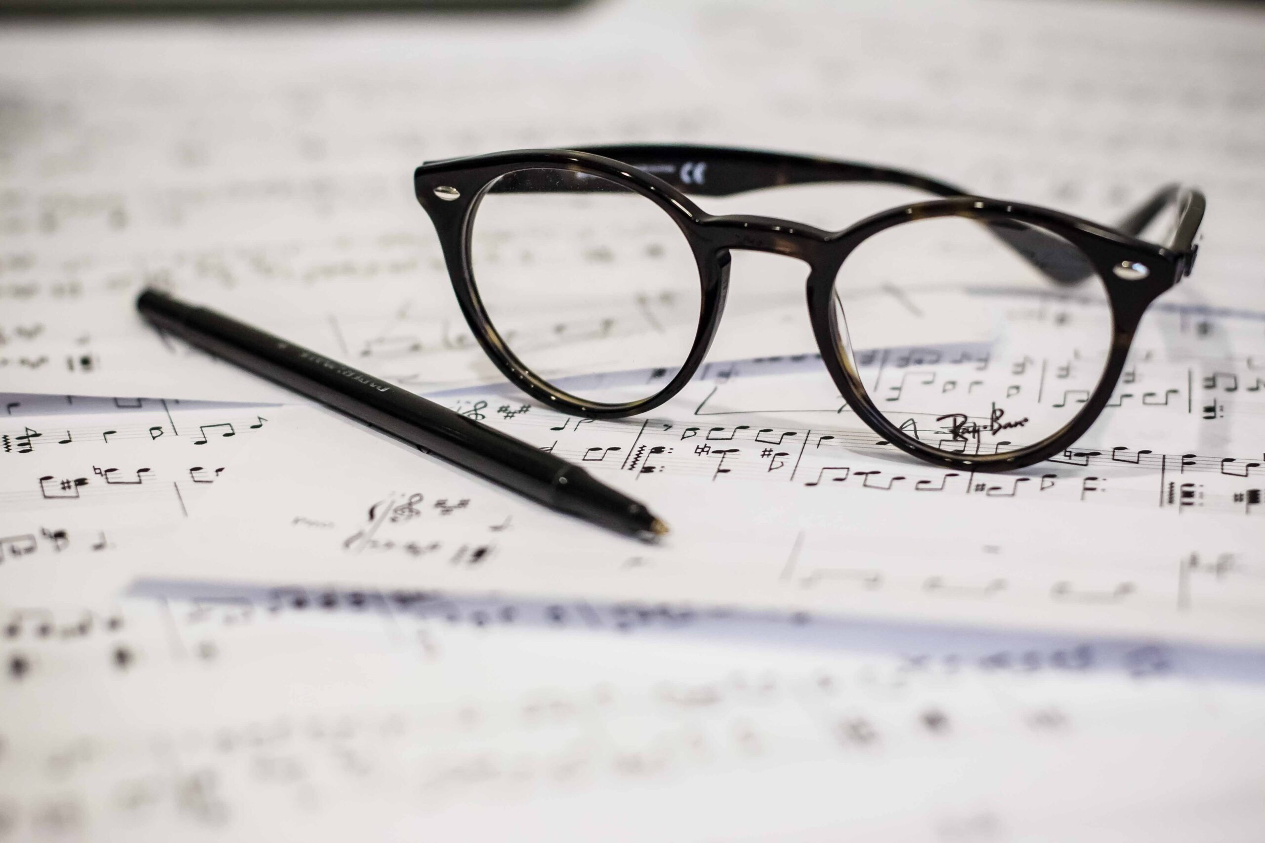 Glasses, pen and music sheets, ready for a music exam.