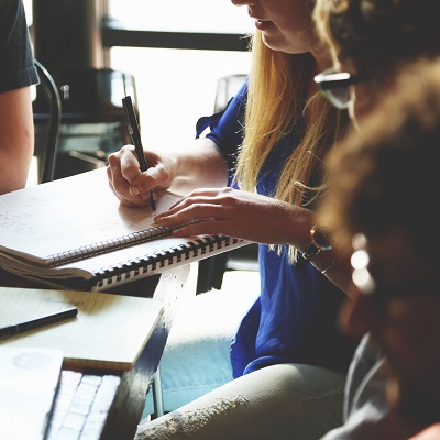 Picture of a group of people on a course, zoomed in on one person writing some notes, symbolising networking.