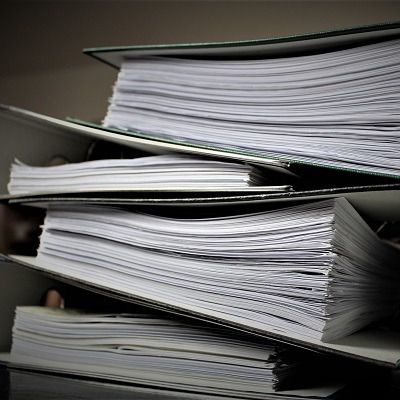 Picture of some folders, filled with files piled up. Symbolises statutory assessment and reporting.