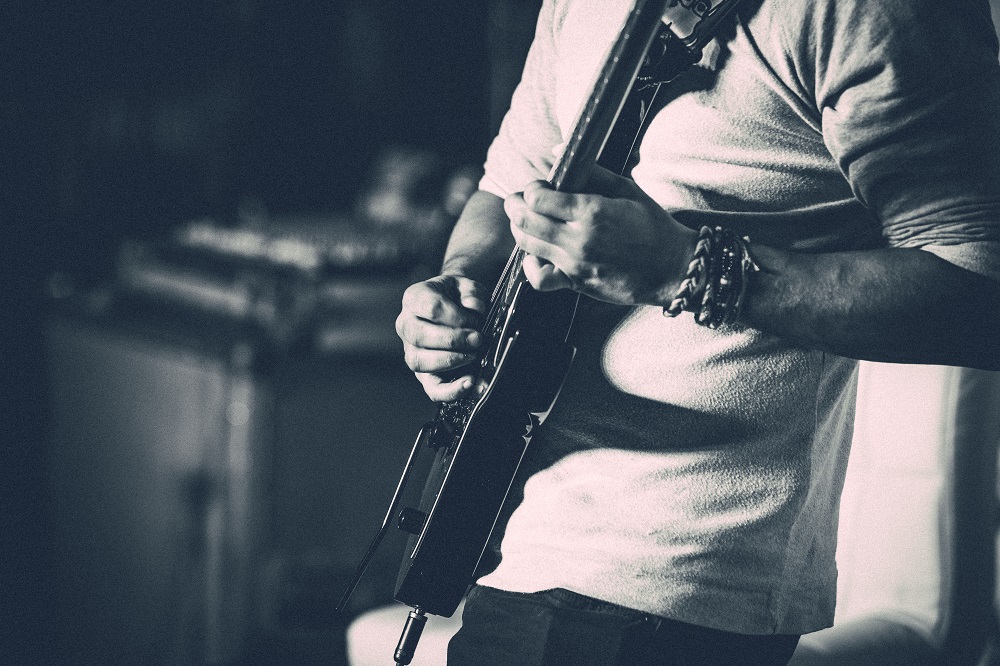 Picture of a man's body playing the guitar - services for education