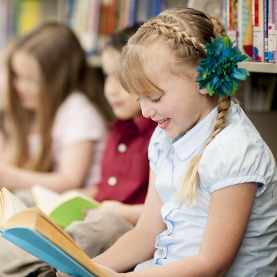 Children sat in the library reading books. Symbolises the range of reading courses we offer