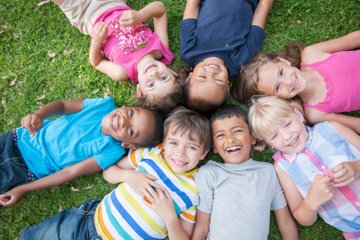 kids lying around in a circle looking happy - services for education