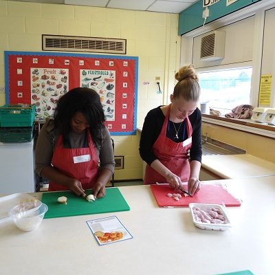 Picture of two health for life delegates cutting up food for a Health For Life practical