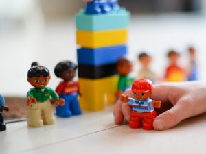 Child's hand playing with some lego bricks and people, symbolising pshe inset training