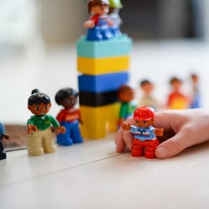 Child's hand playing with some lego bricks and people, symbolising pshe inset training