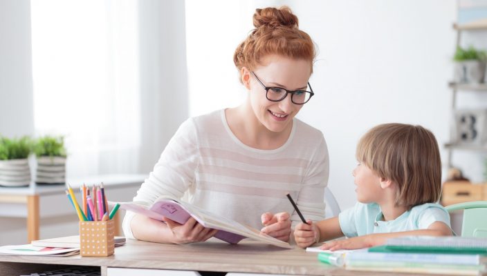 Teacher helping student with their work, both are smiling