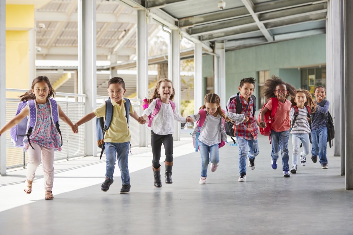 Kids running happily down a corridor holding hands.