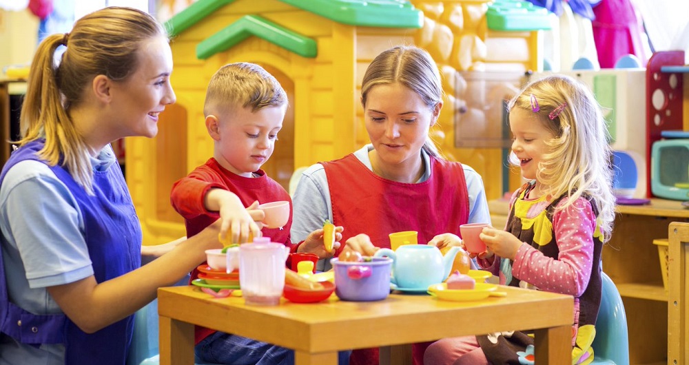 Children playing with teachers and with a toy cooking set