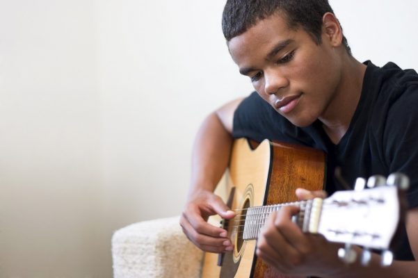 Teenage boy playing guitar at home
