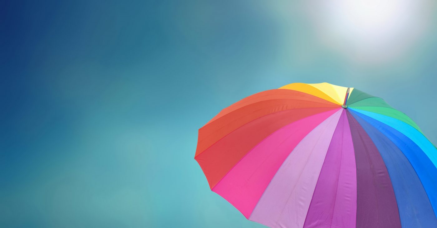 rainbow umbrella under sunny blue sky