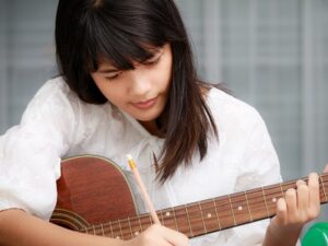 girl holding a guitar and writing notes