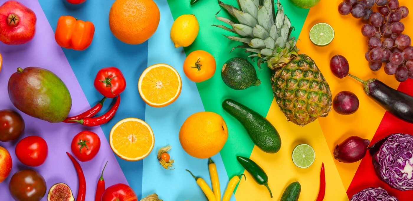 Many different fruits and vegetables on rainbow background